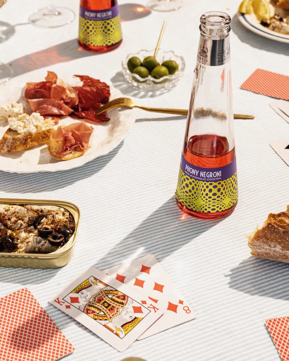 A St. Agrestis Phony Negroni bottle on a hosting table with olives, cured meats, bread and playing cards